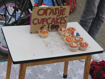 902323 Afbeelding van een tafeltje met 'Oranje Cupcakes' voor 1 euro, op de kindervrijmarkt op het grote parkeerterrein ...